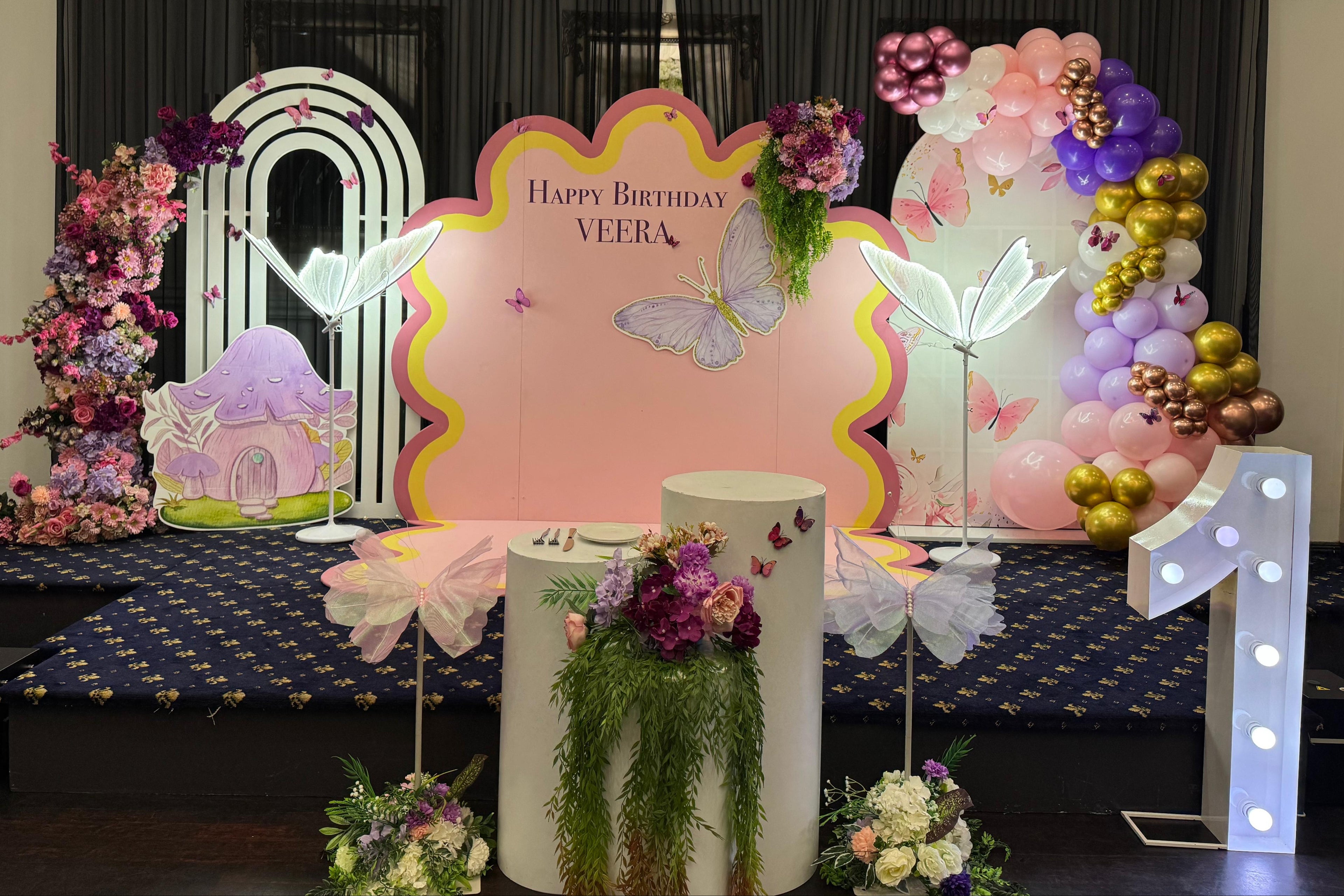 Decorative birthday setup with floral arrangements and a pink birthday sign.